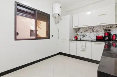 a kitchen with white cabinets and a window at Cosy 2BR Appartment, in City Center, AC, Iptv in Marrakech