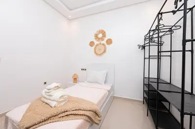 a white bedroom with a bed and a black shelf at Red City Elegant Stay in Marrakech