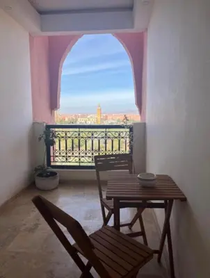 a table and chairs in a room with a balcony at Résidence Caricia - WiFi, Piscine, Parking, Gardien h24 in Marrakech