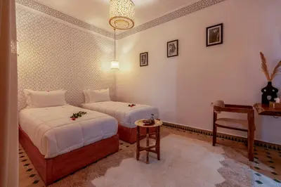 a bedroom with two beds and a table and a chair at Riad Secret De Medina in Marrakech