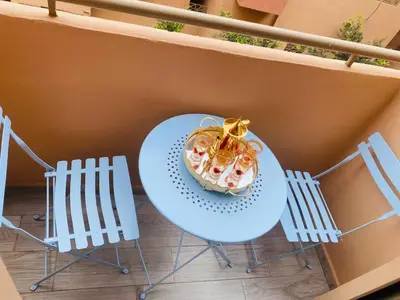 a table with a dessert on a balcony with chairs at Apparemment cosy pour famille in Marrakech