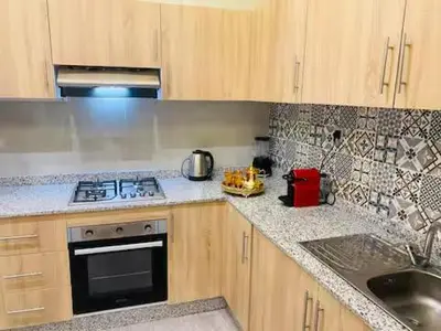 a kitchen with wooden cabinets and a stove and a sink at Apparemment cosy pour famille in Marrakech