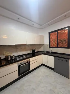 a kitchen with white cabinets and black appliances at Dar des étoiles in Marrakech
