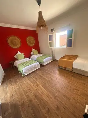 two beds in a room with red walls and wooden floors at Villa Léa 2 Marrakech in Marrakech