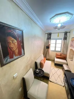 a living room with a painting of a woman on the wall at Riad Elegant suite in the heart of the Medina in Marrakech