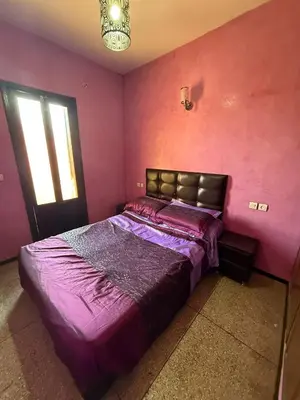 a bedroom with a bed with purple sheets and a window at Location longue durée in Marrakech