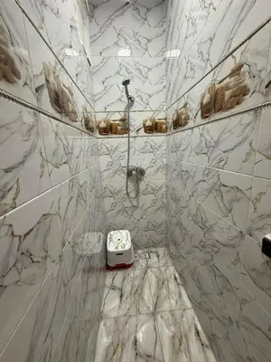 a white marble bathroom with a shower and a sink at Location longue durée in Marrakech