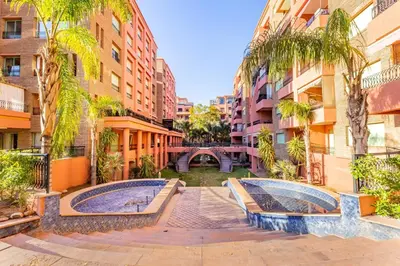a courtyard in a city with buildings and palm trees at Suite Moderne Deluxe Miracle, à Babylone, Hyper-Centre, Marrakesh in Marrakech