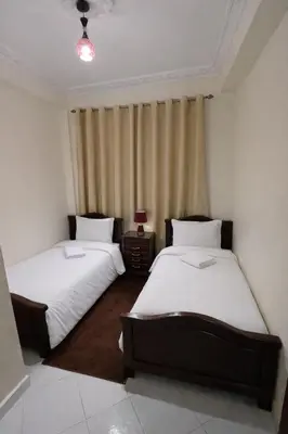 two beds in a small room with a curtain at Bel Appart 2 chambres à 10 min à pied de RAK in Marrakech