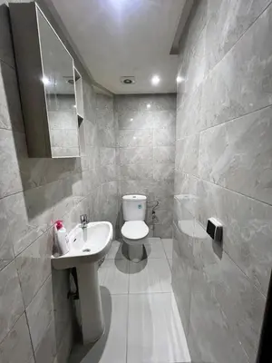 a white bathroom with a toilet and a sink at Bel Appart 2 chambres à 10 min à pied de RAK in Marrakech