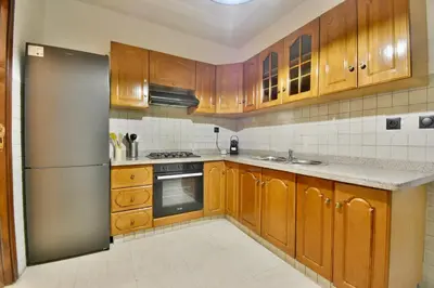 a kitchen with wooden cabinets and a stainless steel refrigerator at L'adresse- Appartement 4p au centre de Marrakech in Marrakech