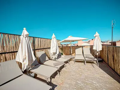 a row of chairs and umbrellas on a deck at Riad Louzaia, Marrakech in Marrakech