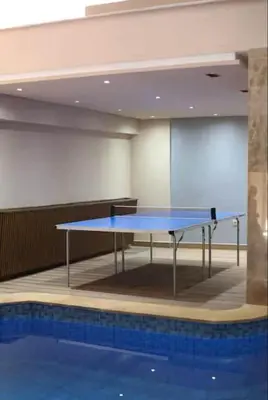 a ping pong table in a room next to a pool at Gueliz apartment with pool, spa and gym in Marrakech