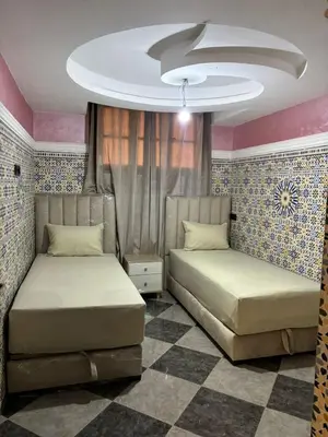 a bedroom with two beds and a ceiling at Un appartement au rez-de-chaussée dans une maison in Marrakech