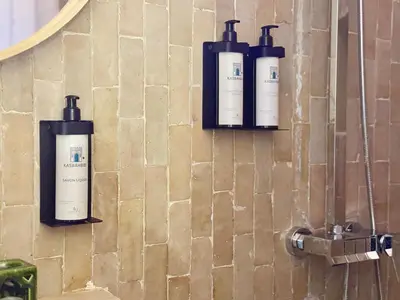 three bottles on the wall of a bathroom at Kasbahbibi pool breakfast city center private in Marrakech