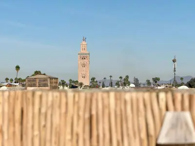 a clock tower in the distance behind a wooden fence at Kasbahbibi pool breakfast city center private in Marrakech