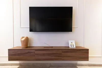 a tv on a wall with a wooden dresser at grand studio hypercentre de marrakech et proche gare in Marrakech