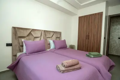 a purple bed with two towels on top of it at Oasis Urban avec Balcon - 5min de l'aéroport in Marrakech