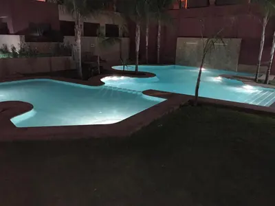 a group of three swimming pools at night at Appartement moderne terrasse avec baignoire privée in Marrakech