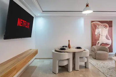 a living room with a table and chairs and a sign at Appartement Luxe Gueliz Piscine & Spa in Marrakech