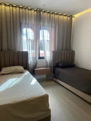 a bedroom with two beds and a window with curtains at Jennaya - Appartement moderne, élégant et raffiné in Marrakech