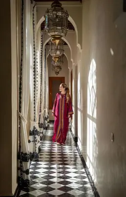 a woman walking down a hallway in a building at Daba Village in Marrakech