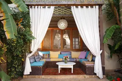 a patio with a couch and a table and curtains at Daba Village in Marrakech