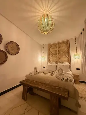 a bedroom with a large bed and a chandelier at Riad Dar Siyah in Marrakech