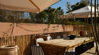 a wooden table with chairs and an umbrella at Riad Dar Siyah in Marrakech
