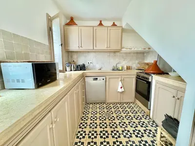 a kitchen with white cabinets and a black and white tile floor at Maison Remedy et Spa Private Pool & Breakfast in Marrakech