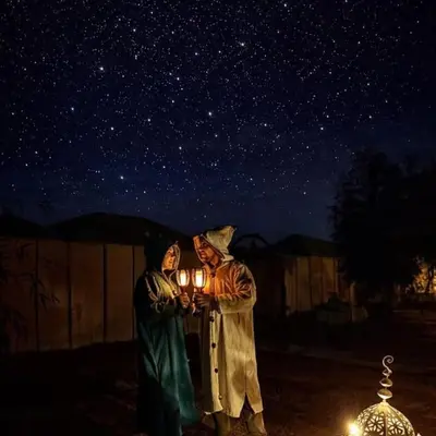 two people standing under a starry sky holding lights at Yassen luxury camp in Marrakech