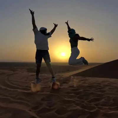 two people jumping in the sand in the desert at Yassen luxury camp in Marrakech