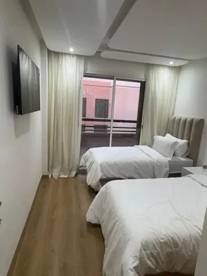 a hotel room with two beds and a window at Appartement moderne avec terrasse vue piscine in Marrakech