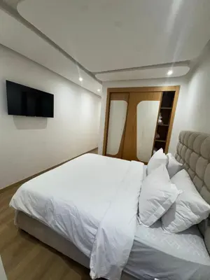 a bedroom with a white bed and a flat screen tv at Appartement moderne avec terrasse vue piscine in Marrakech