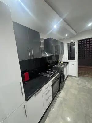 a kitchen with white cabinets and black counter tops at Appartement moderne avec terrasse vue piscine in Marrakech