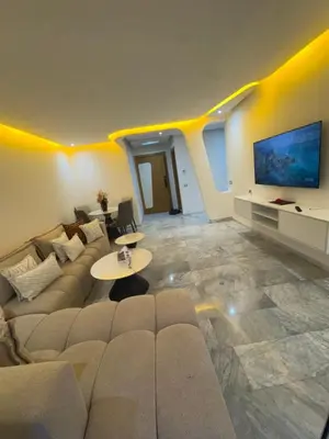 a living room with a couch and a tv at Appartement moderne avec terrasse vue piscine in Marrakech