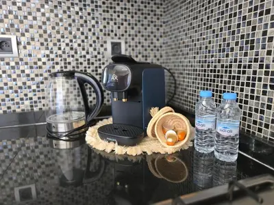 a coffee maker on a counter with bottles of water at Jubaea Prestigia Cosy appartement avec vue sur Atlas à Marrakech in Marrakech