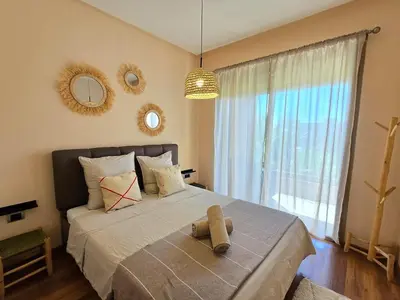 a bedroom with a large bed with a large window at Jubaea Prestigia Cosy appartement avec vue sur Atlas à Marrakech in Marrakech