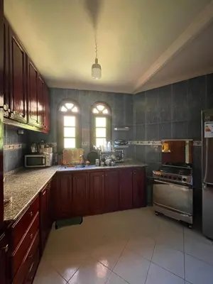 a large kitchen with wooden cabinets and a refrigerator at Villa Familiale in Marrakech