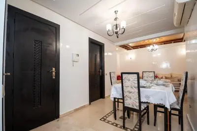 a dining room with a table and chairs and a black door at Calm Apartment with Pool in Geuliz marrakech Close to Medina in Marrakech