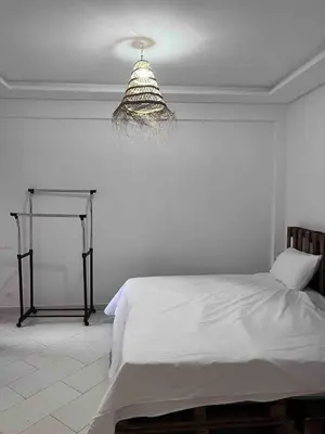 a white bedroom with a bed and a chandelier at Modern quiet studio Close to Guéliz in Marrakech