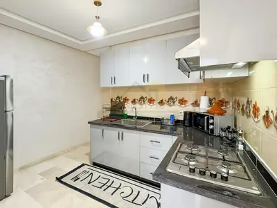 a kitchen with white cabinets and a black counter top at Séjour chic au cœur de Marrakech in Marrakech