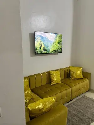 a living room with a brown couch and a flat screen tv at Modern Apartment & 8 min from Marrakech Airport in Marrakech