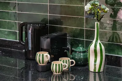 a vase with flowers and cups on a counter at Studio élégant et paisible au cœur de Marrakech in Marrakech