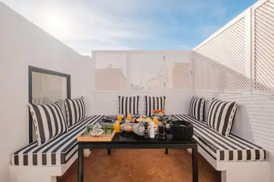 a balcony with a table and striped chairs on a balcony at Riad Alaya in Marrakech