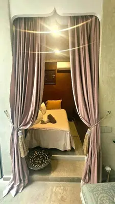 a small bedroom with a bed with purple curtains at Douiria des Loulous in Marrakech