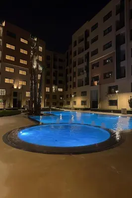 a large blue pool in front of some buildings at night at Appartement Haut standing Gueliz, Piscines, jacuzzi chauffé & Fitness in Marrakech