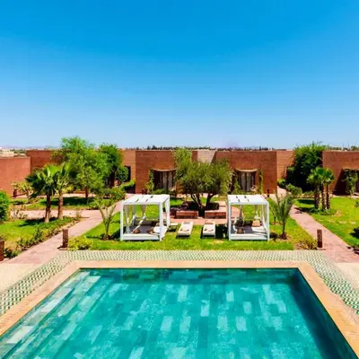 a swimming pool with two gazebos next to a building at Villa Romana in Marrakech