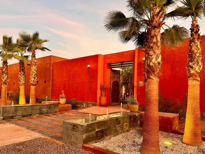 a red building with palm trees in front of it at Villa Romana in Marrakech