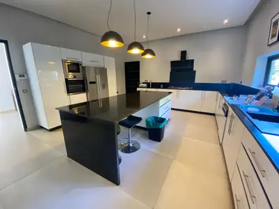 a large kitchen with a black counter top and white cabinets at Villa Ines Piscine chauffée & Jacuzzi & Hammam in Marrakech